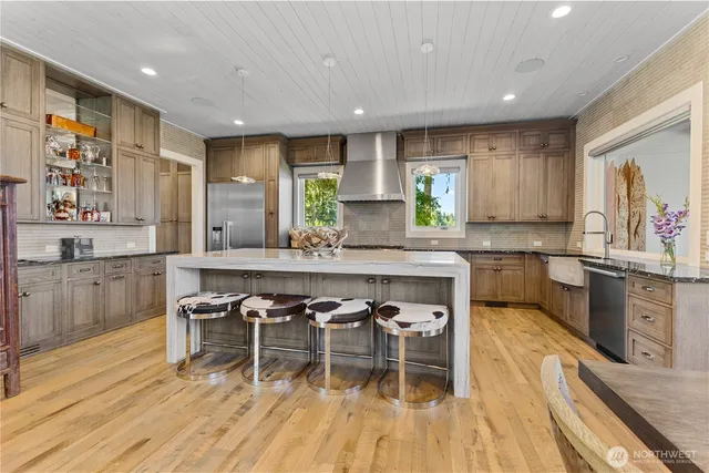a kitchen with stainless steel appliances a dining table chairs and sink