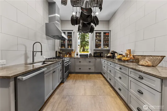 a kitchen with stainless steel appliances granite countertop a sink a stove and a wooden floors