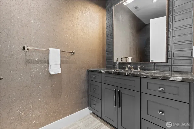 a bathroom with a granite countertop sink a mirror and a shower