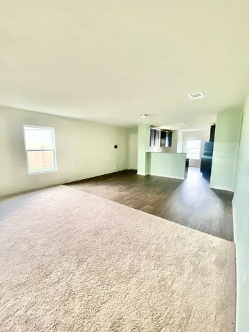 a view of a big room with wooden floor and a kitchen