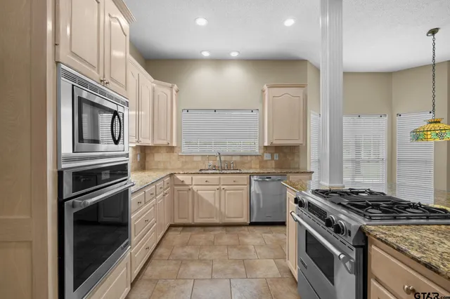 a kitchen with stainless steel appliances granite countertop a stove a sink and white cabinets with wooden floor