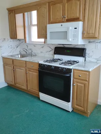 a kitchen with granite countertop a stove a sink and a microwave