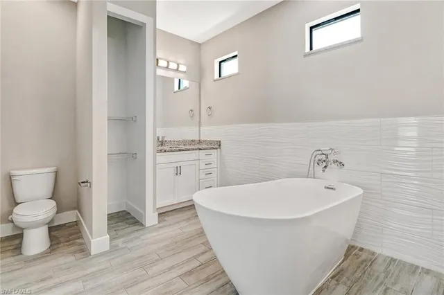 a spacious bathroom with a white toilet a sink and a mirror
