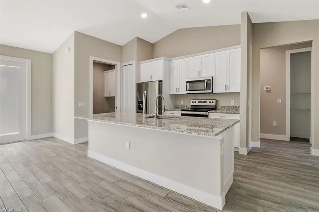 a kitchen with stainless steel appliances kitchen island granite countertop a stove a sink and a refrigerator