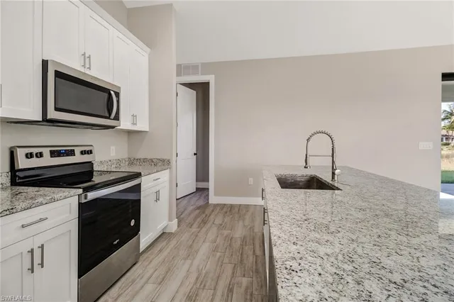 a kitchen with stainless steel appliances granite countertop a stove a sink and a microwave