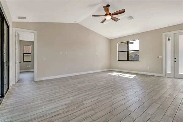 an empty room with wooden floor and windows