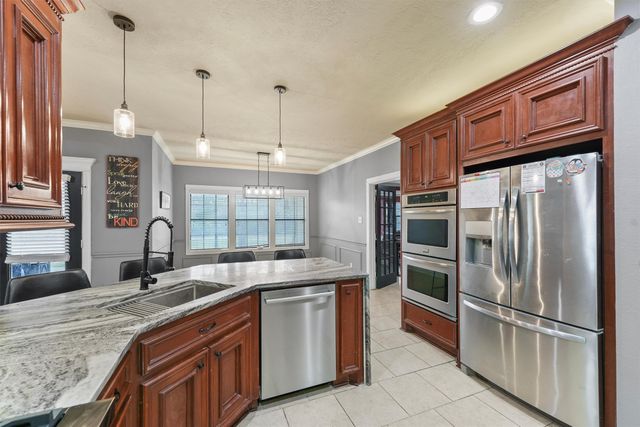 a kitchen with stainless steel appliances granite countertop a sink refrigerator and cabinets