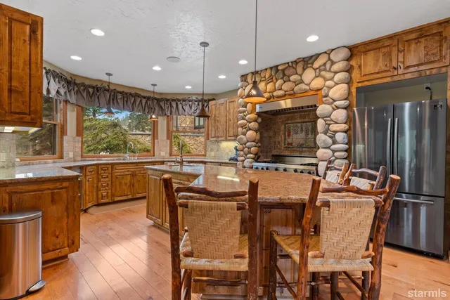 a kitchen with stainless steel appliances granite countertop a sink a stove top oven a chimney and a dining table