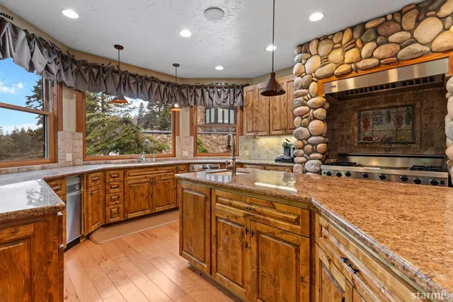 a kitchen with stainless steel appliances granite countertop a sink a stove and a wooden floors