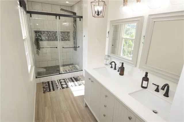 a bathroom with a granite countertop sink a mirror and shower