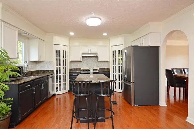 a kitchen with stainless steel appliances a refrigerator a stove a sink dishwasher and a dining table with wooden floor