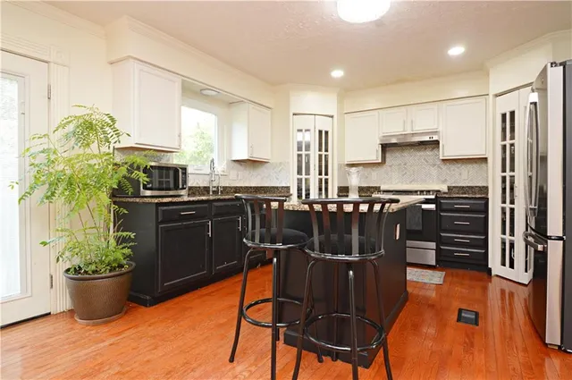 a kitchen with stainless steel appliances granite countertop a stove top oven a sink a dining table and chairs