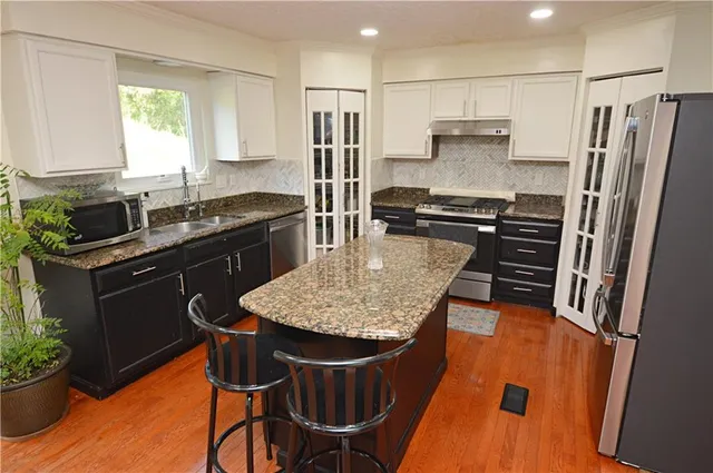 a kitchen with stainless steel appliances granite countertop a sink stove and refrigerator