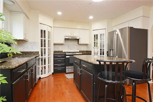 a kitchen with stainless steel appliances granite countertop a stove a sink and a refrigerator