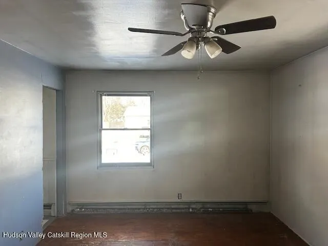 an empty room with a window and a fan