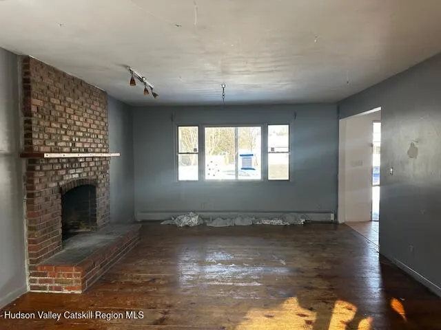 a view of empty room with wooden floor and fireplace