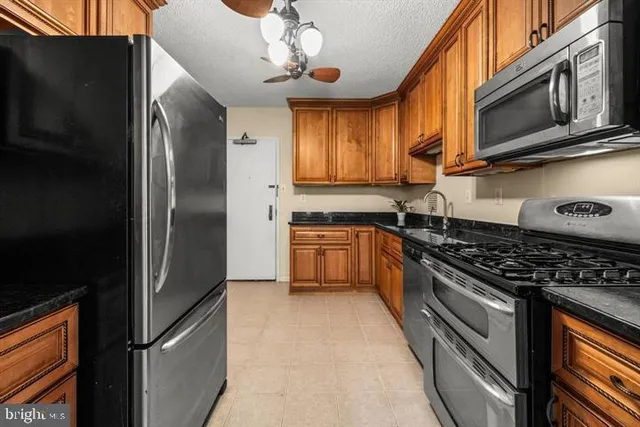 a kitchen with stainless steel appliances granite countertop a stove top oven a refrigerator and dishwasher with wooden floor