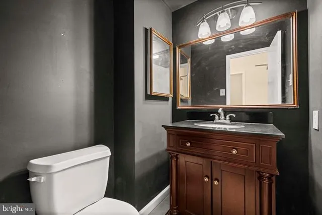 a bathroom with a granite countertop toilet a sink and a mirror