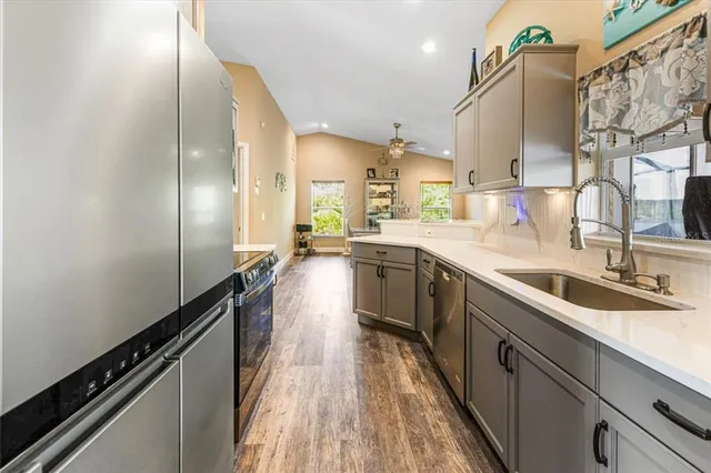 a kitchen with stainless steel appliances granite countertop a refrigerator a stove and a sink with wooden floor