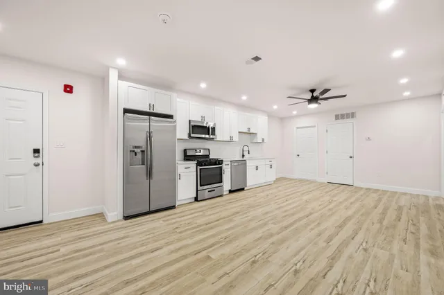 a kitchen with stainless steel appliances kitchen island a refrigerator sink and cabinets