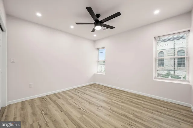 an empty room with wooden floor ceiling fan and windows