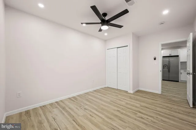 an empty room with wooden floor and a ceiling fan
