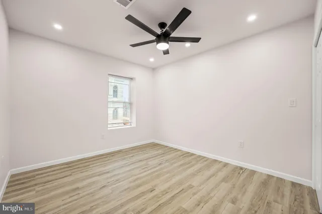 an empty room with wooden floor and ceiling fan