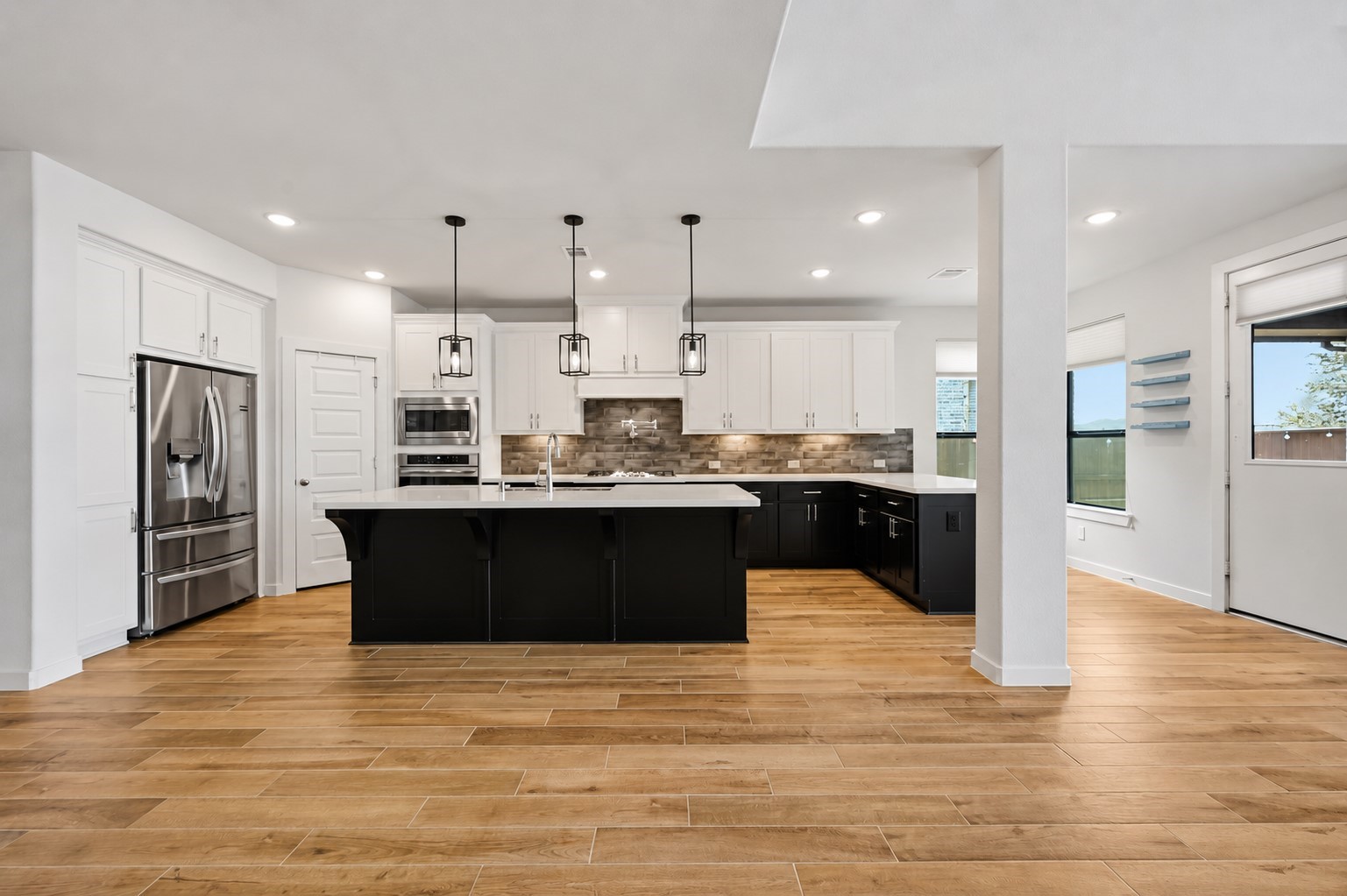 6718 Waxbill Road Katy, TX 77493 - Photo 5 of 30 The kitchen boasts a deco wood paneled island with sleek pendant lighting and extended peninsula for extra countertop space. Upgraded with built-in stainless steel appliances, a 5 burner gas cooktop, and contrasting cabinets, this kitchen is ideal for cooking for the whole family or hosting holidays!