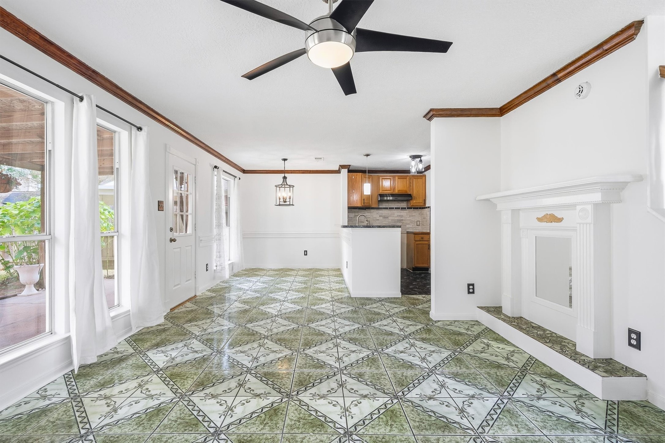 5426 Bourgeois Road Houston, TX 77066 - Photo 9 of 43 Spacious open-concept living area featuring decorative tile flooring, a modern ceiling fan, and abundant natural light from large windows, seamlessly connected to a cozy kitchen with warm wooden cabinetry.