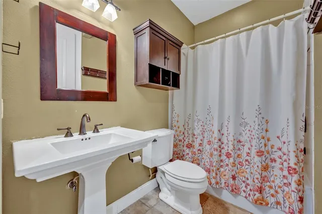a bathroom with a sink a toilet and shower curtain