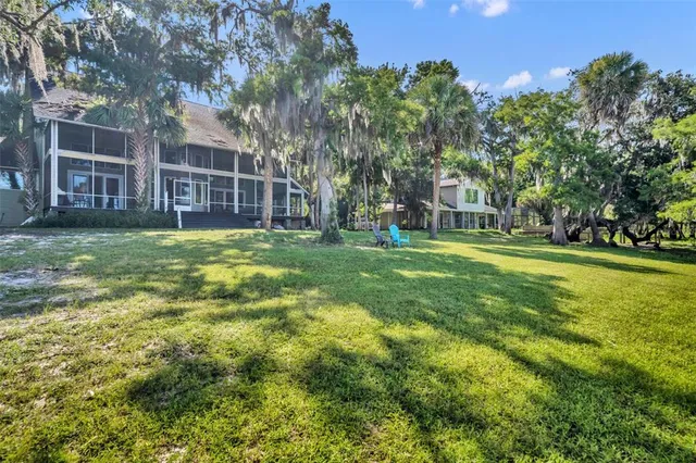 a view of a house with a big yard and large trees