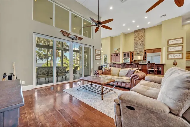 a living room with furniture large windows and wooden floor