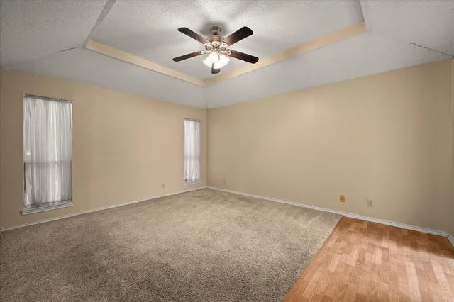 an empty room with ceiling fan and window
