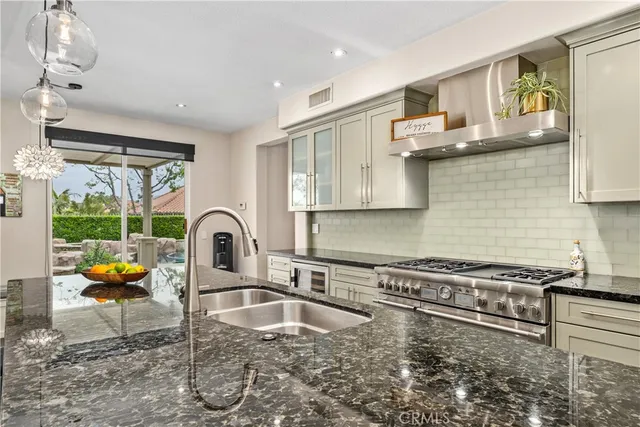 a kitchen with stainless steel appliances granite countertop a stove a sink and a wooden cabinets