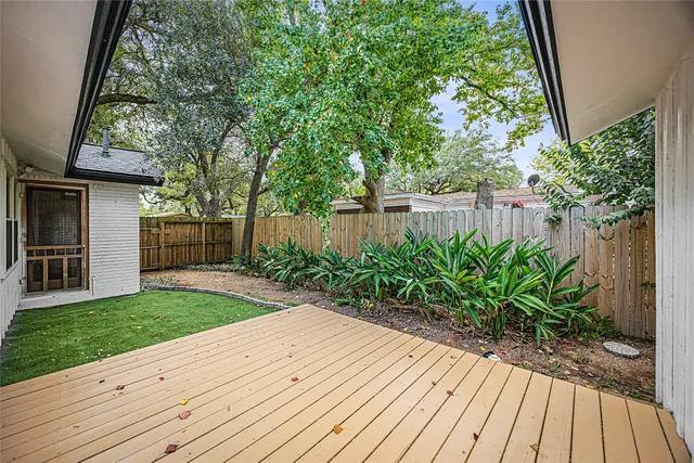 a view of a backyard with plants and large trees with wooden fence