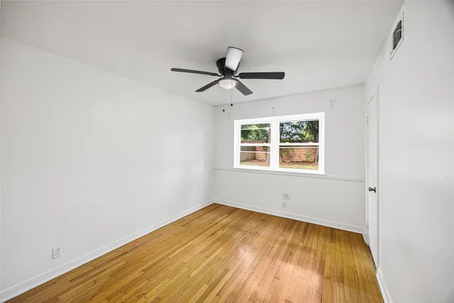 an empty room with a window and ceiling fan