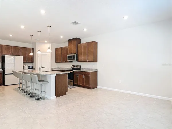 a kitchen with stainless steel appliances kitchen island granite countertop a stove a sink a refrigerator and a microwave