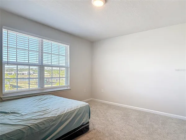 a bed sitting in a spacious bedroom next to a window
