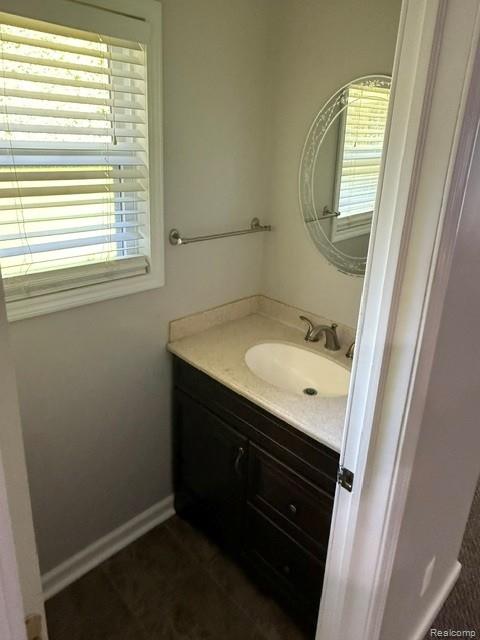 465 Trombley Road Troy, MI 48083 - Photo 20 of 24 Window with blinds, vanity with integrated sink, dark wood-finish cabinetry, light-toned countertop, and an oval wall mirror
