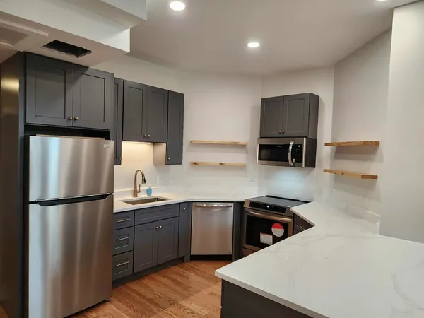 a large kitchen with a large counter top stainless steel appliances and cabinets