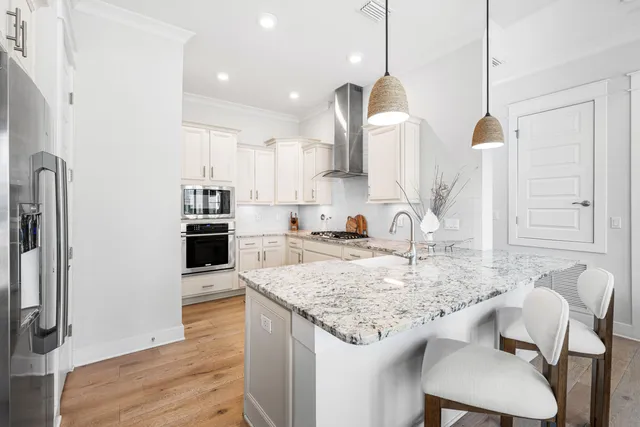 a kitchen with stainless steel appliances kitchen island granite countertop a sink stove and white cabinets