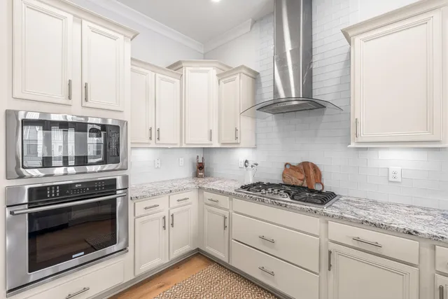 a kitchen with stainless steel appliances granite countertop a sink a stove and a wooden floor