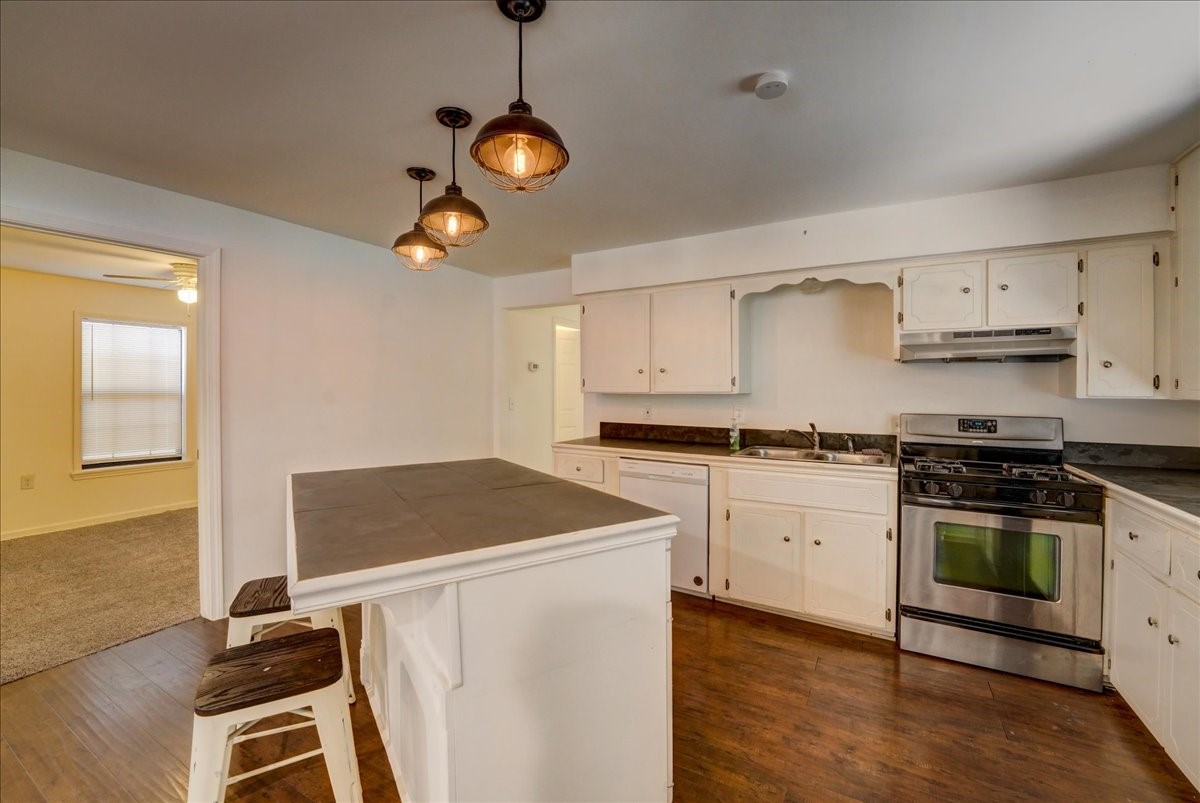 1105 East 3rd Street Austin, TX 78702 - Photo 4 of 40 a kitchen with stainless steel appliances granite countertop a stove a sink dishwasher and white cabinets with wooden floor
