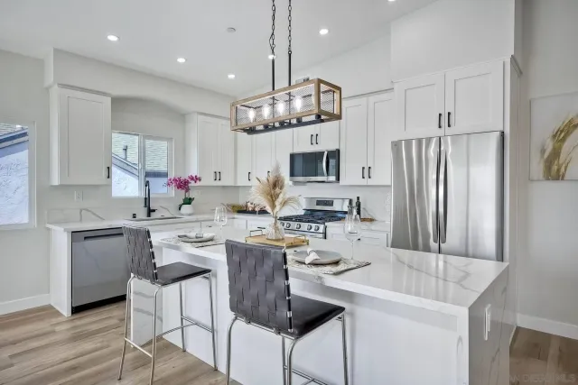 a kitchen with stainless steel appliances kitchen island granite countertop a table chairs and a refrigerator