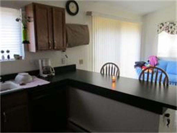 61 Round House Road, Unit 61 Bourne, MA 02532 - Photo 4 of 7 a kitchen with stainless steel appliances a sink dishwasher a stove a dining table and chairs with wooden floor