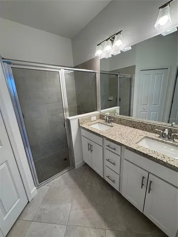 a spacious bathroom with a granite countertop sink a mirror and shower