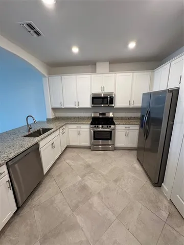 a large kitchen with stainless steel appliances and white cabinets