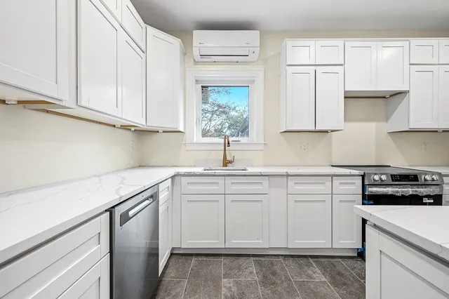 a kitchen with white cabinets appliances a sink and a window