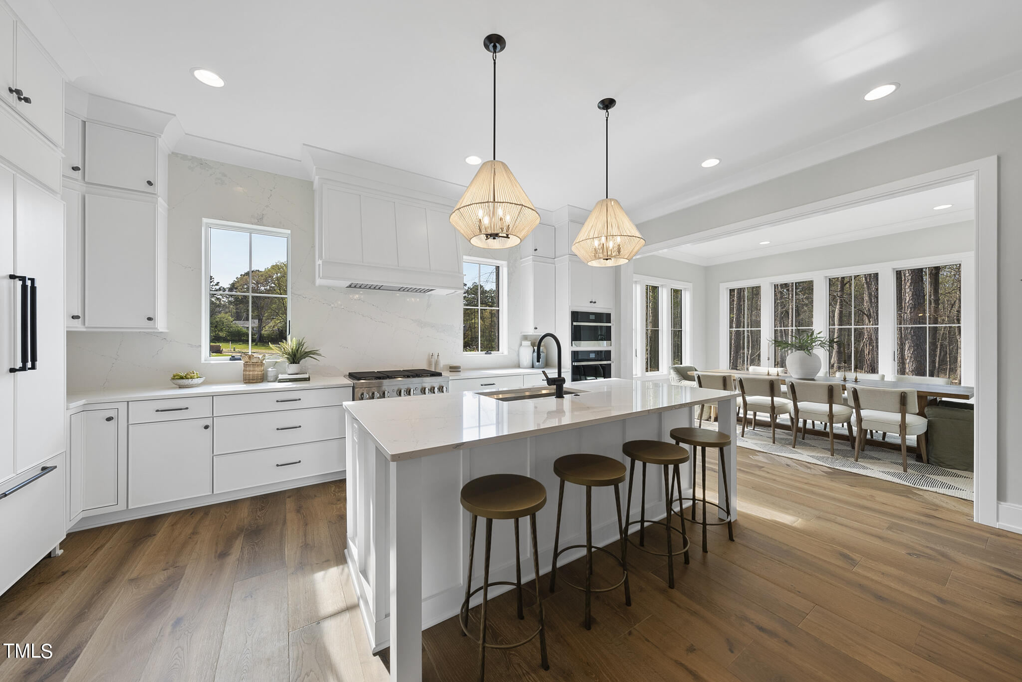 3409 Makers Circle Raleigh, NC 27612 - Photo 13 of 100 a large white kitchen with a large island oven a sink dishwasher a dining table and chairs with wooden floor