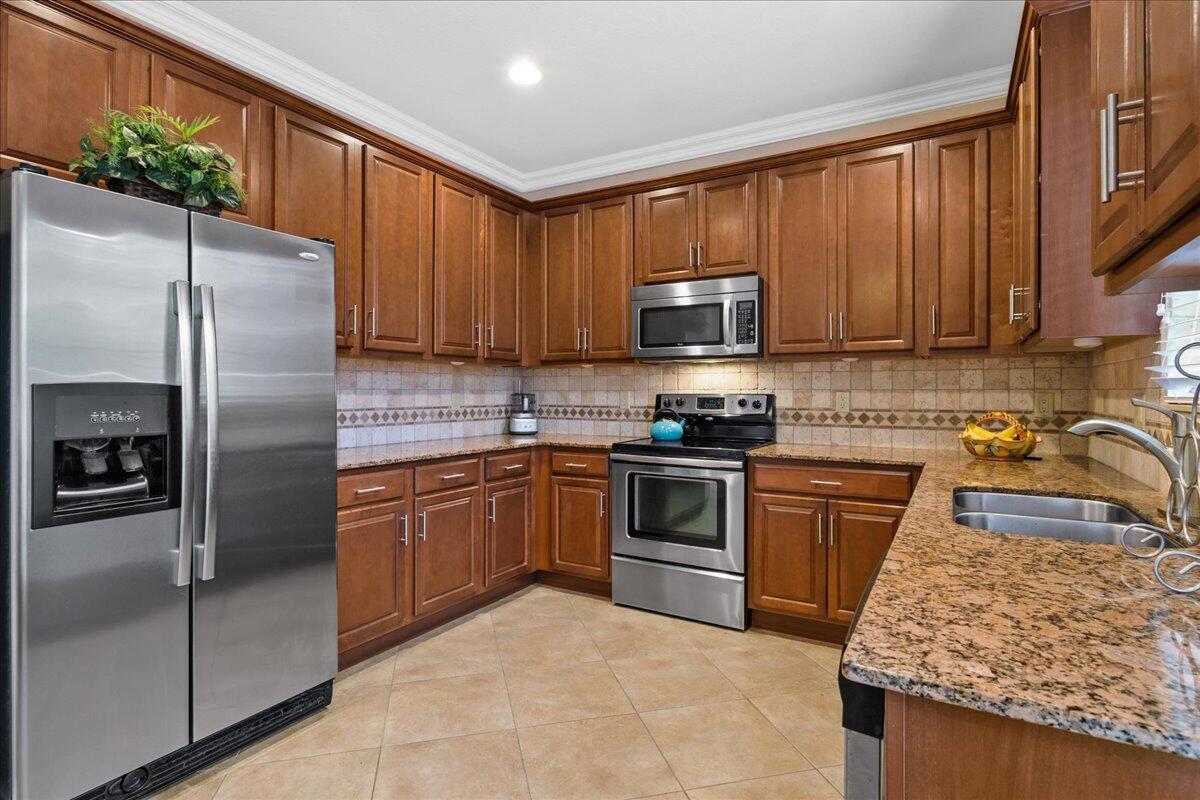 603 Dakota Drive Jupiter, FL 33458 - Photo 2 of 34 a kitchen with granite countertop a refrigerator stove top oven a sink and dishwasher